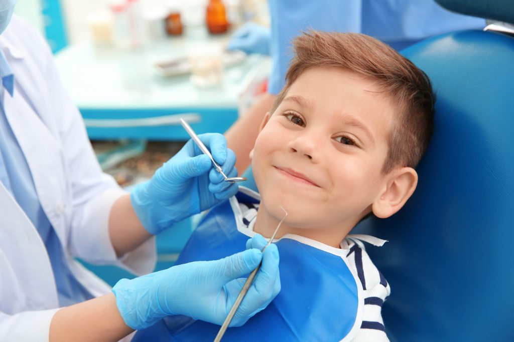 Photo of a smiling redheaded boy in the dentist chair, learning about preventing toothaches through good oral care.